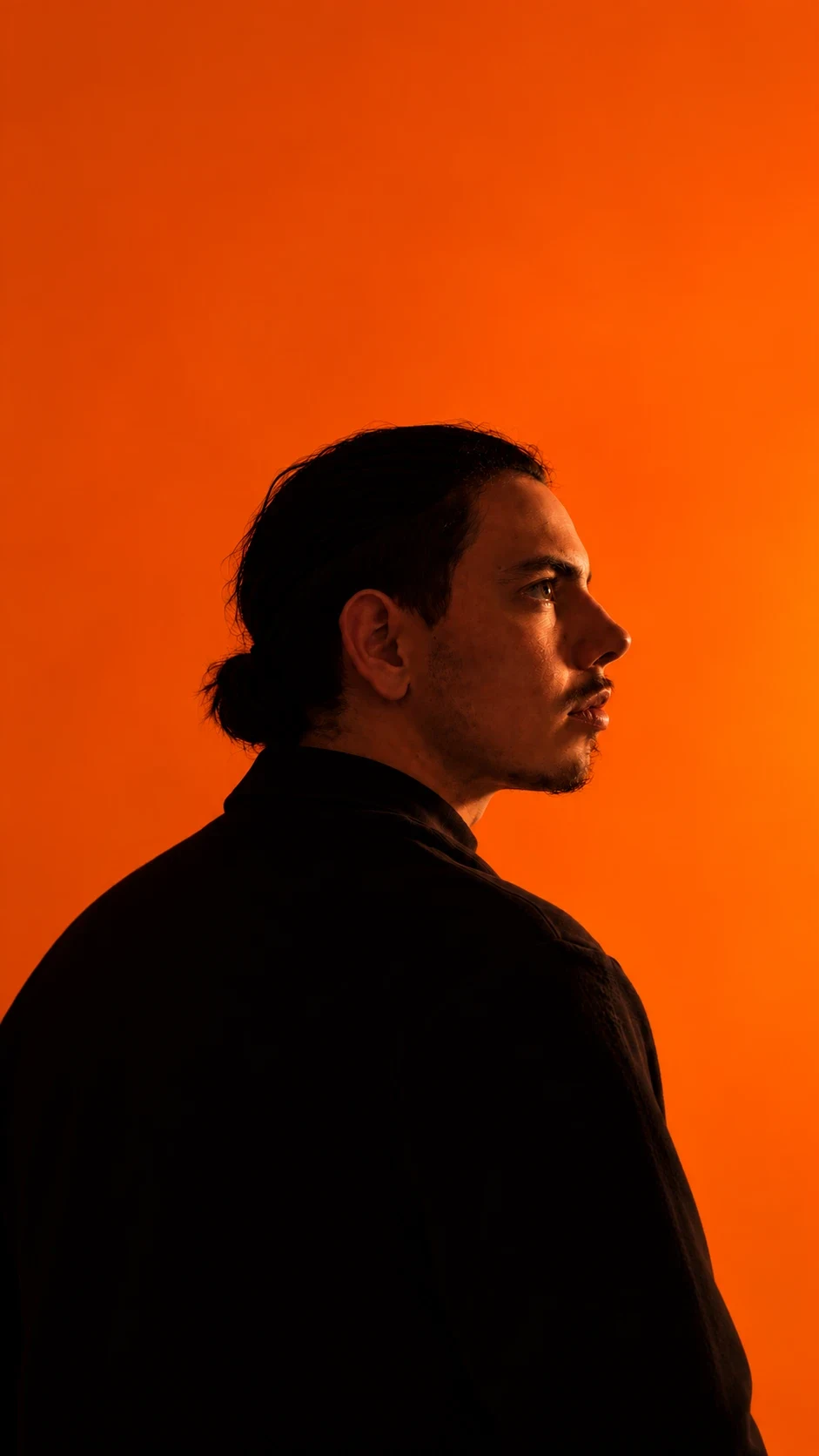 Thomas, de profil, sur un fond orange