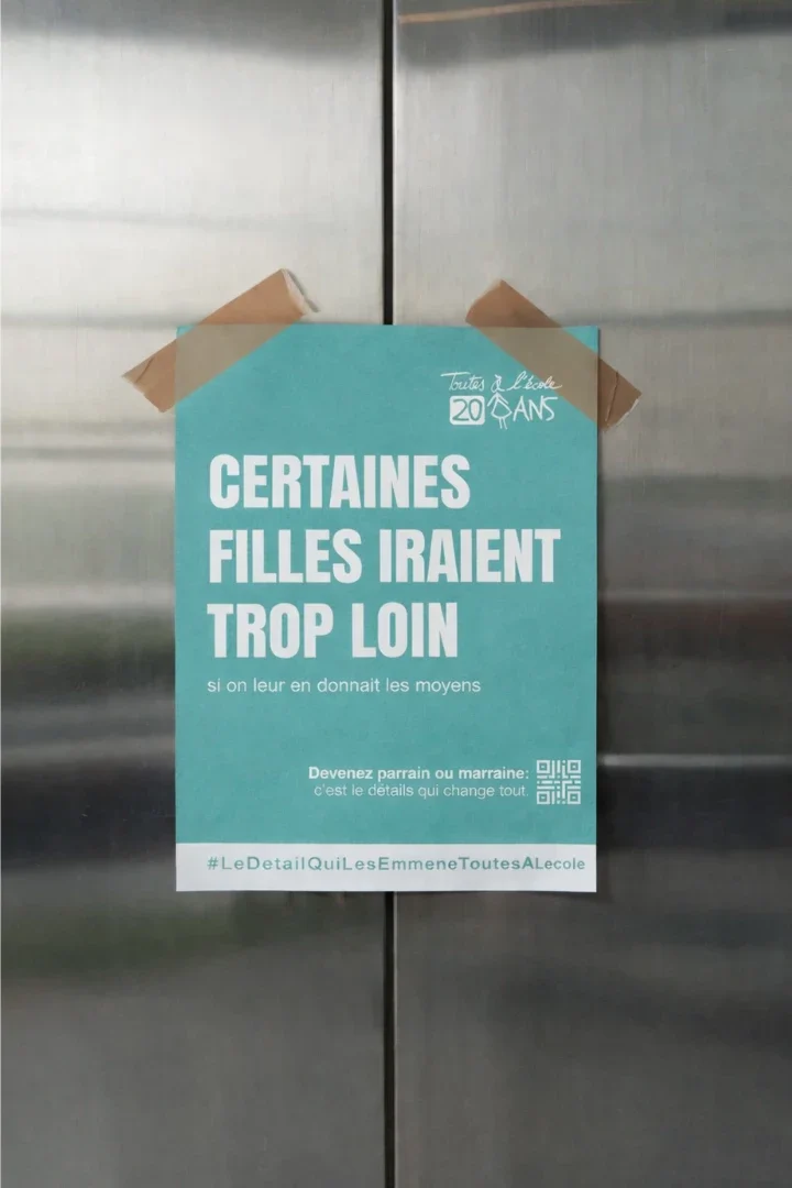Affiche Toutes à l'école collée sur une porte d'ascenseur : « Certaines filles iraient trop loin si on leur en donnait les moyens »